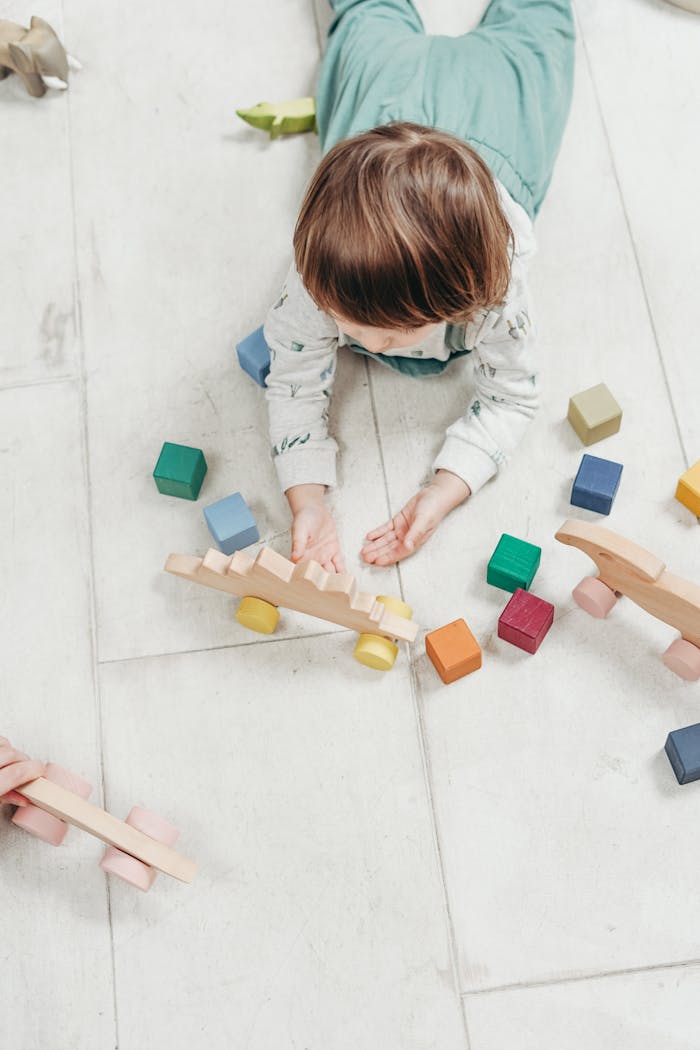Home Child playing with colorful wooden toys on a light floor, creating a fun and educational setting.