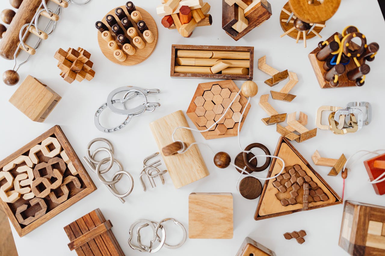 Home Top view of various wooden brain teaser puzzles on a white table, showcasing unique designs and playful challenges.
